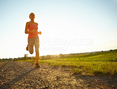 Buy stock photo A young woman running along a dirt road