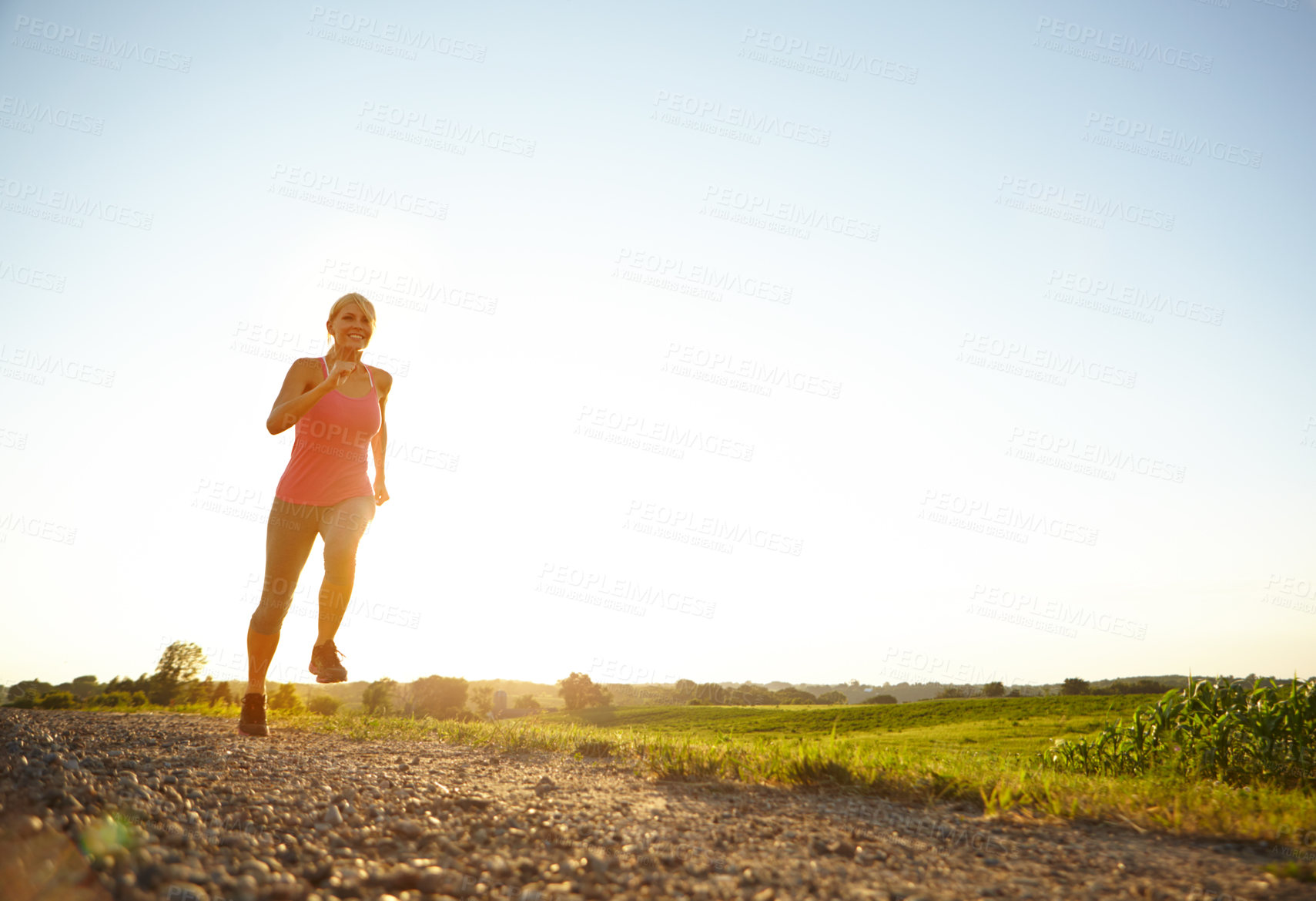 Buy stock photo A young woman running along a dirt road