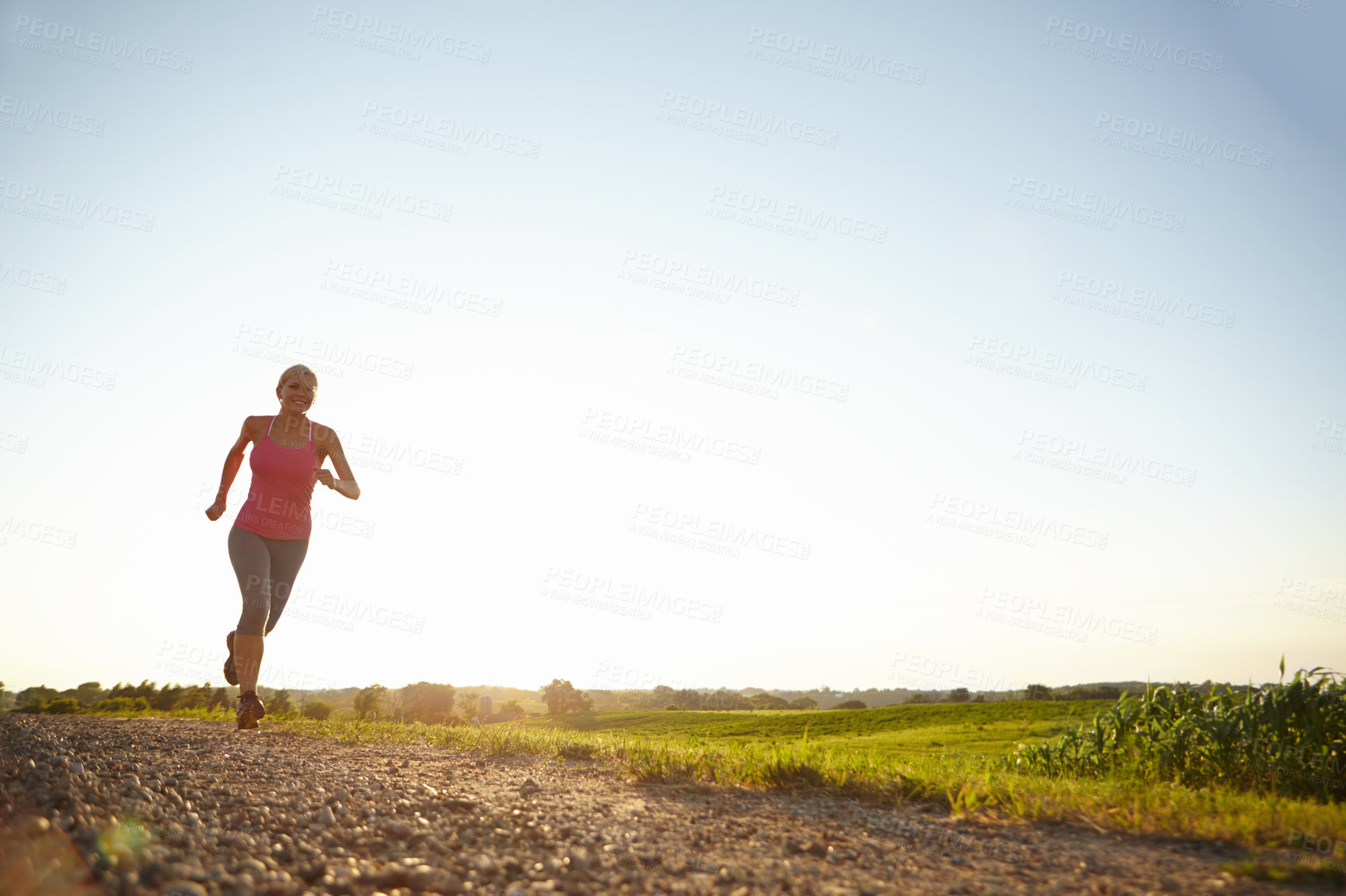 Buy stock photo A young woman running along a dirt road