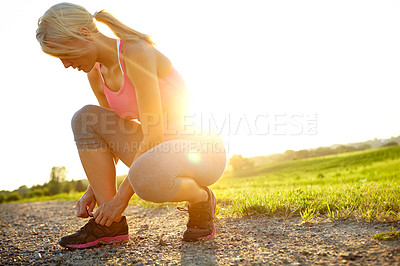 Buy stock photo A young woman in sportswear tying her shoelaces