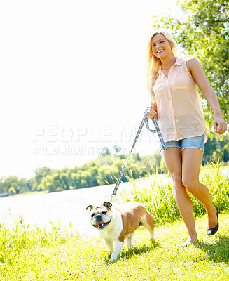 Buy stock photo A beautiful blonde taking her dog for a walk in a park