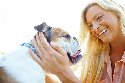 Buy stock photo A happy blonde laughing while playing with her dog outside