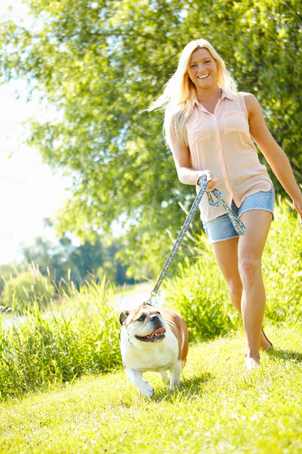 Buy stock photo A beautiful blonde taking her dog for a walk in a park