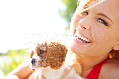 Buy stock photo Portrait of a happy woman holding a puppy while relaxing outside 