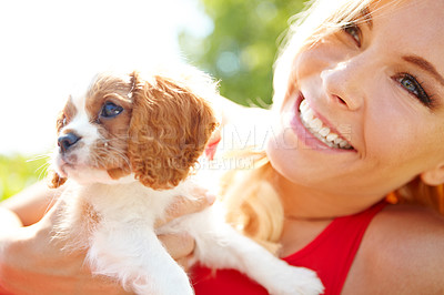 Buy stock photo Shot of a smiling woman holding a cute puppy while relaxing outside