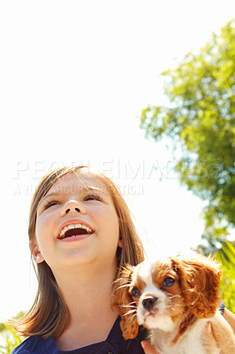 Buy stock photo Shot of a happy little girl holding a puppy while standing outside