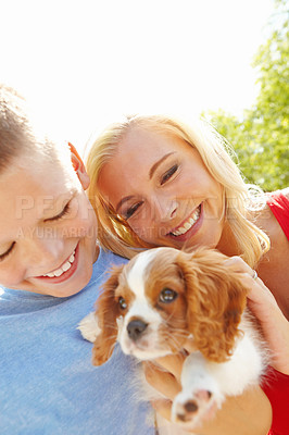 Buy stock photo Shot of a smiling boy with his mother holding a puppy while they stand outside