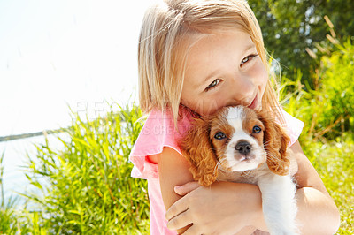 Buy stock photo Shot of a cute little girl hugging her puppy outdoors