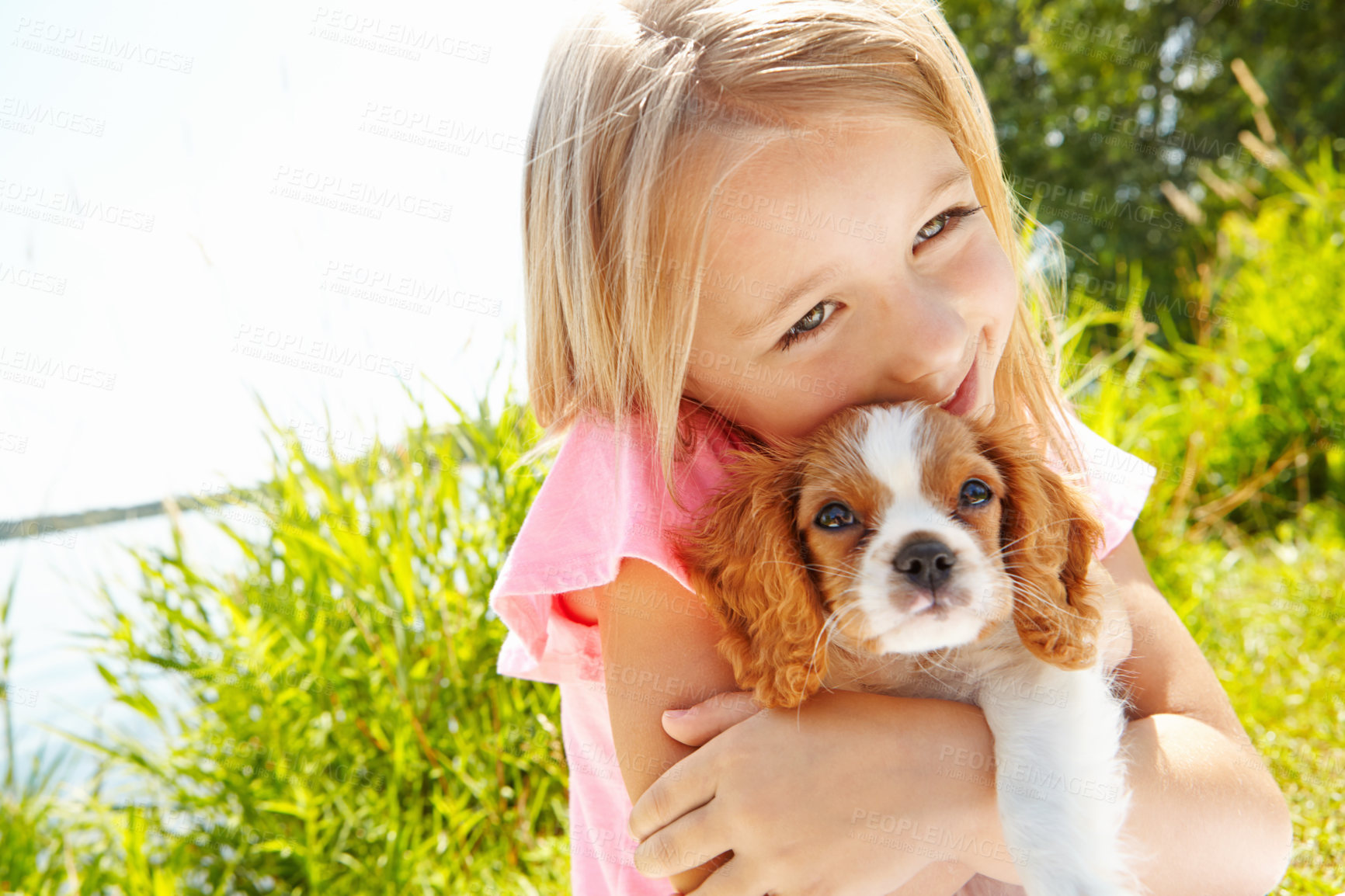 Buy stock photo Shot of a cute little girl hugging her puppy outdoors