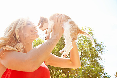 Buy stock photo Shot of a beautiful happy woman standing outside and holding her puppy up with copyspace