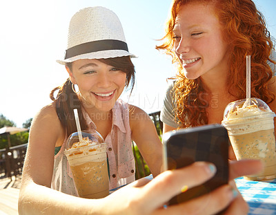 Buy stock photo Cafe, phone and smile of girl best friends drinking ice coffee outdoor in park together for break. App, relax and social media with happy teens at table in nature for bonding or text message