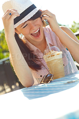 Buy stock photo An adolescent girl laughing as she speaks on her cellphone while sitting at an outdoor cafe