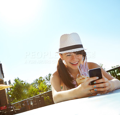 Buy stock photo A happy teenage girl texting on a smartphone while enjoying a smoothie at an outdoor cafe