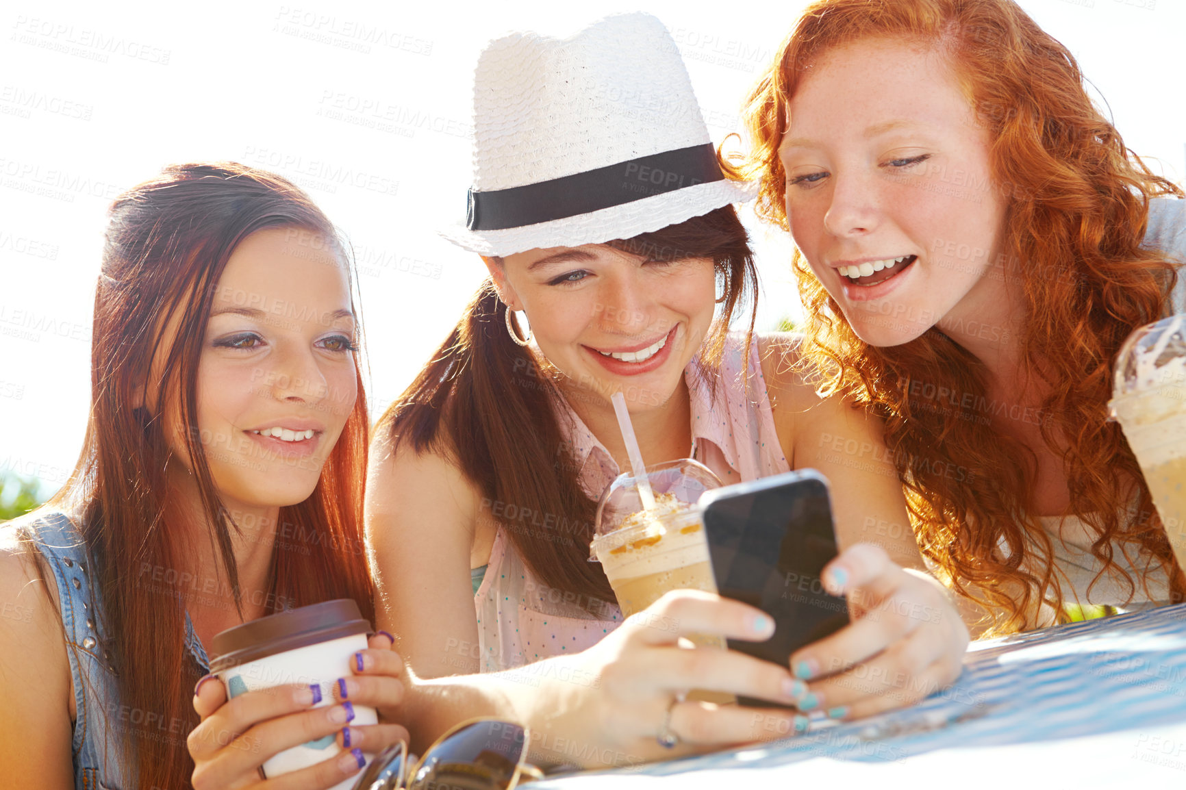 Buy stock photo Three adolescent girls sitting at an outdoor cafe texting on a cellphone