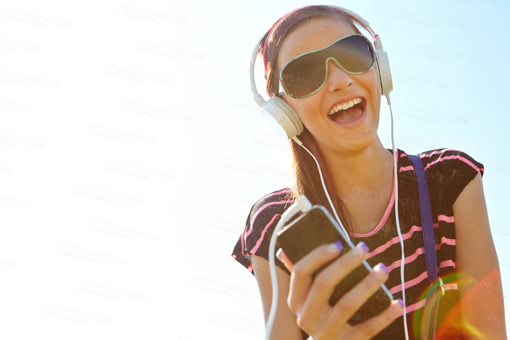 Buy stock photo A happy young teeanage girl listening to music over her headphones