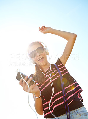 Buy stock photo A happy young teenage girl dancing outside while listening to music on her headphones