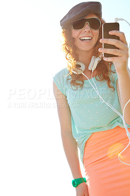 Buy stock photo A redheaded adolescent girl selecting a playlist on her smartphone while standing outside