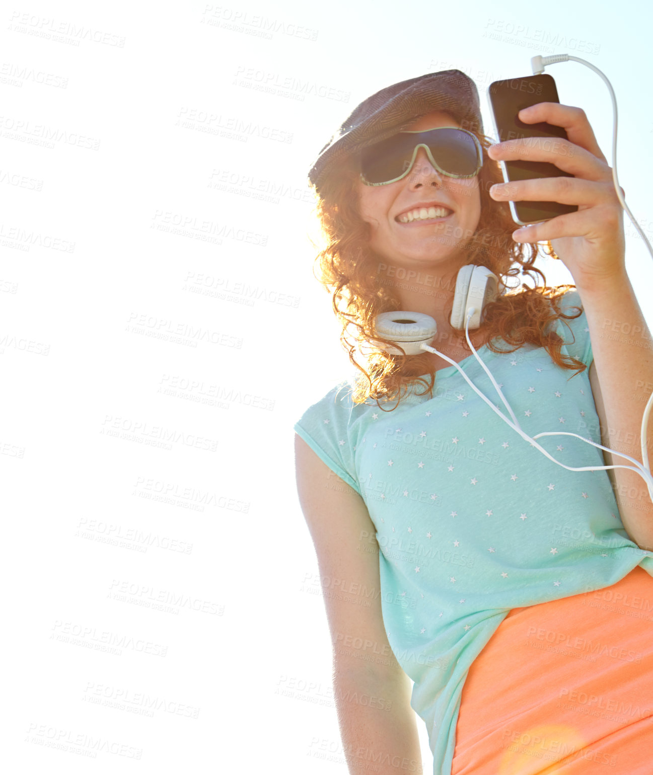 Buy stock photo A redheaded adolescent girl selecting a playlist on her smartphone while standing outside