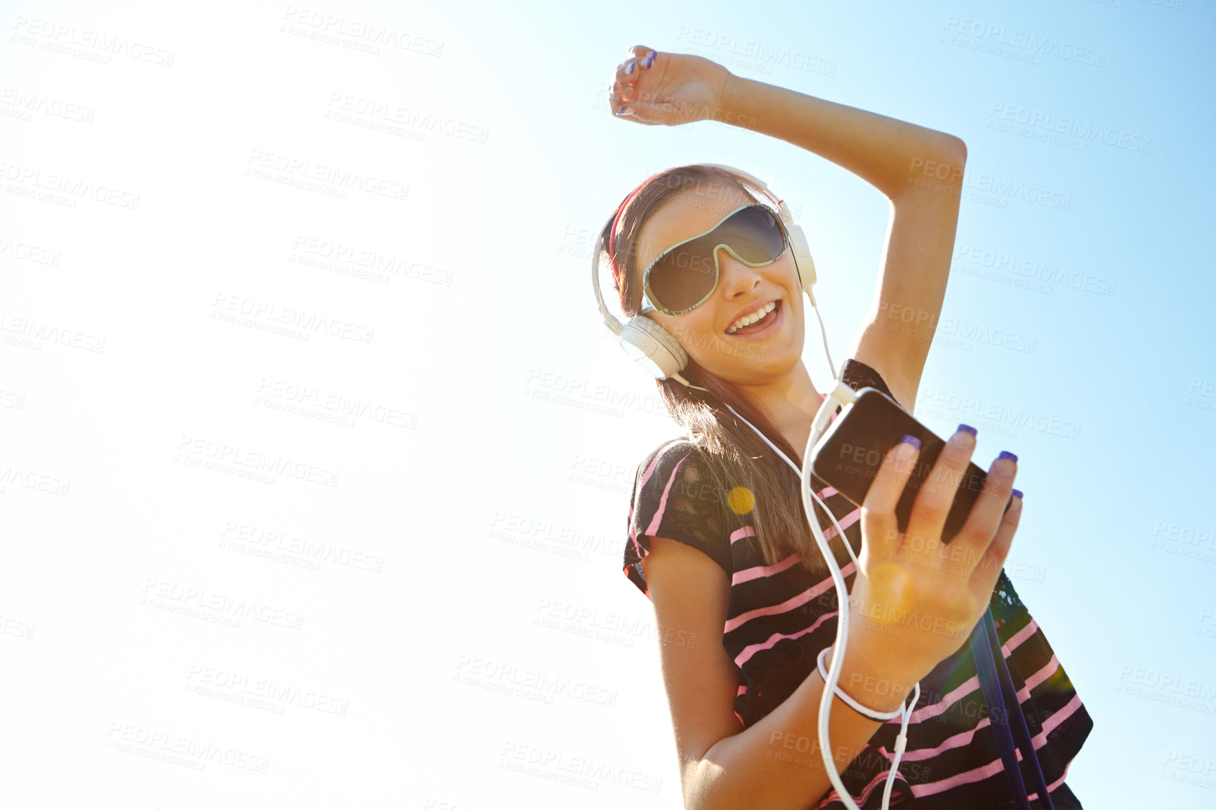 Buy stock photo A happy young teenage girl dancing outside while listening to music on her headphones