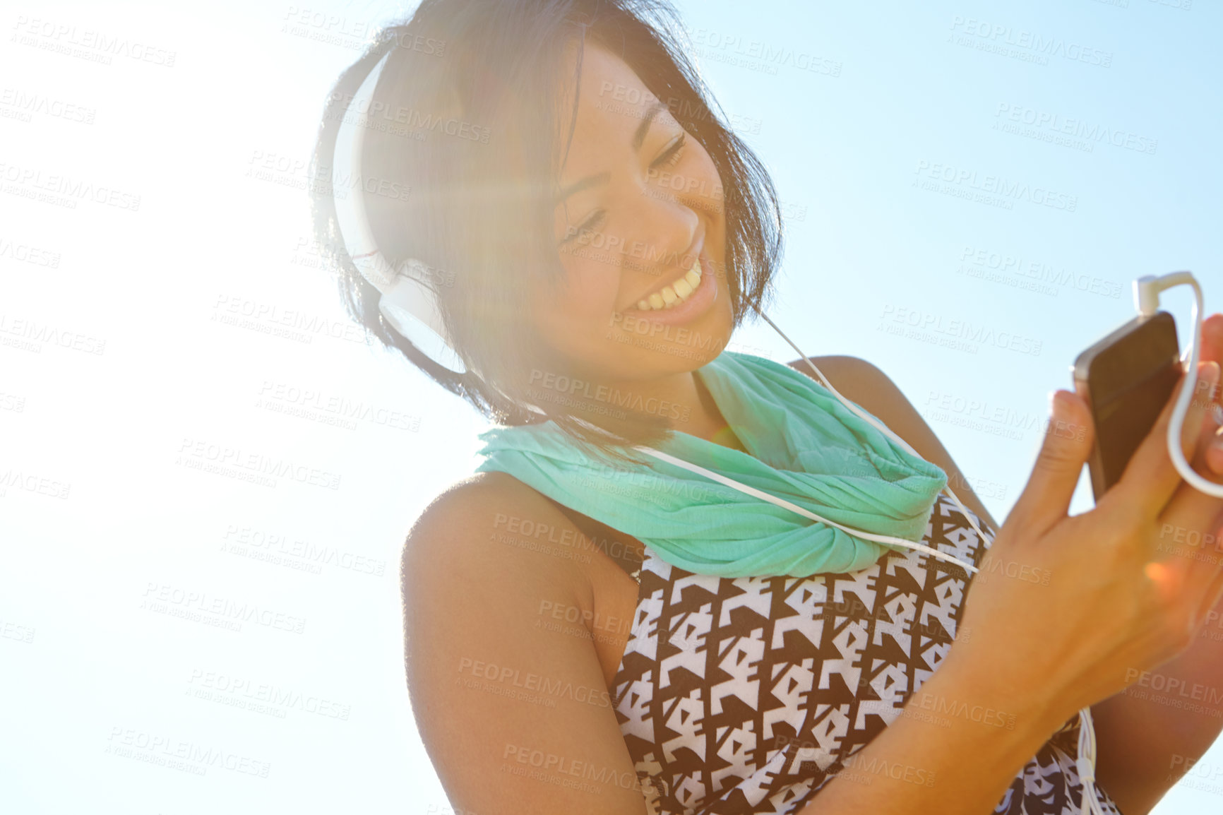 Buy stock photo A happy young ethnic adolescent girl listening to music on her headphones