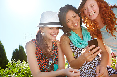 Buy stock photo Girls, park and phone with smile, reading together and comic meme on social network app. Happy teenagers, smartphone and group of friends with funny video, notification or web blog for outdoor travel