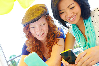 Buy stock photo Two teenage girls sitting outside texting on their cellphones