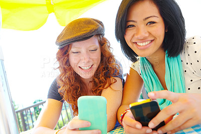 Buy stock photo Two teenage girls sitting outside texting on their cellphones