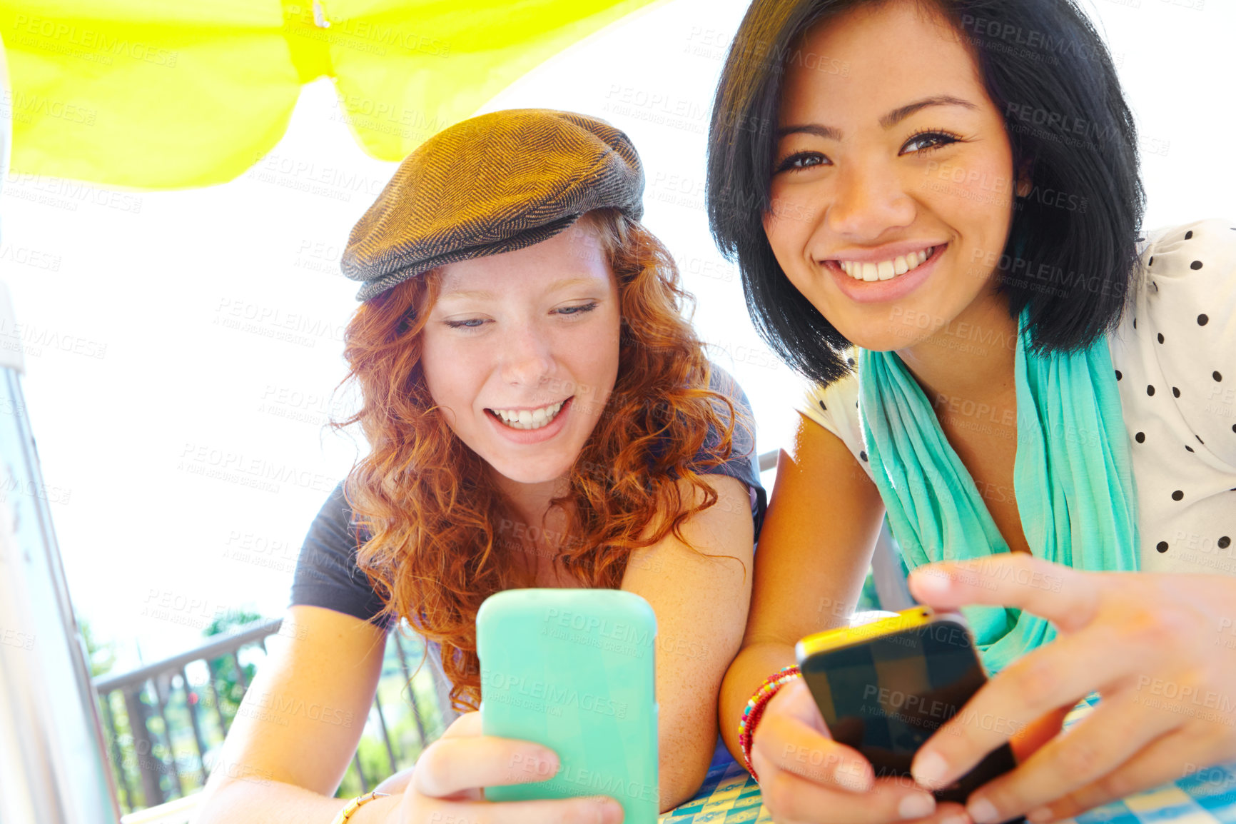 Buy stock photo Two teenage girls sitting outside texting on their cellphones