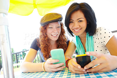 Buy stock photo Two teenage girls sitting outside texting on their cellphones