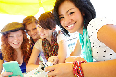 Buy stock photo A group of adolescent girls laughing as they look at something on a smartphone screen