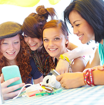 Buy stock photo A group of adolescent girls laughing as they look at something on a smartphone screen