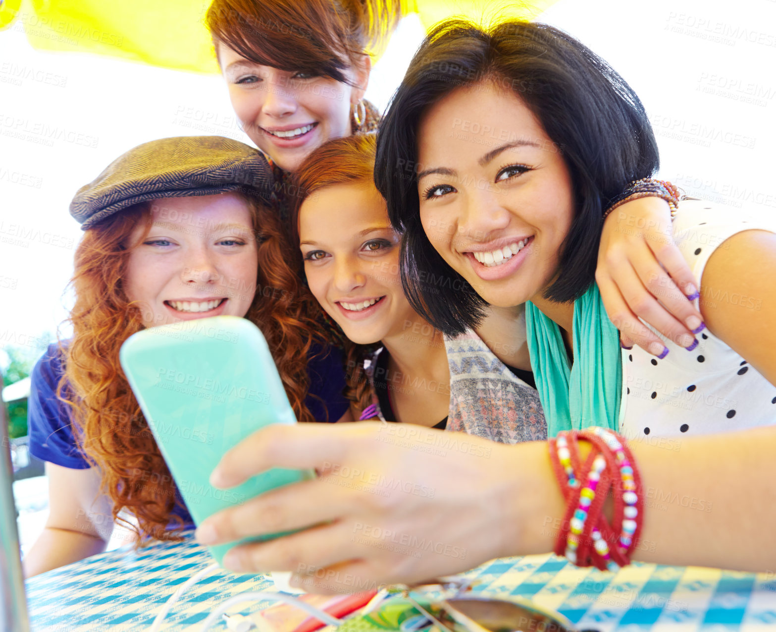 Buy stock photo A group of adolescent girls laughing as they look at something on a smartphone screen