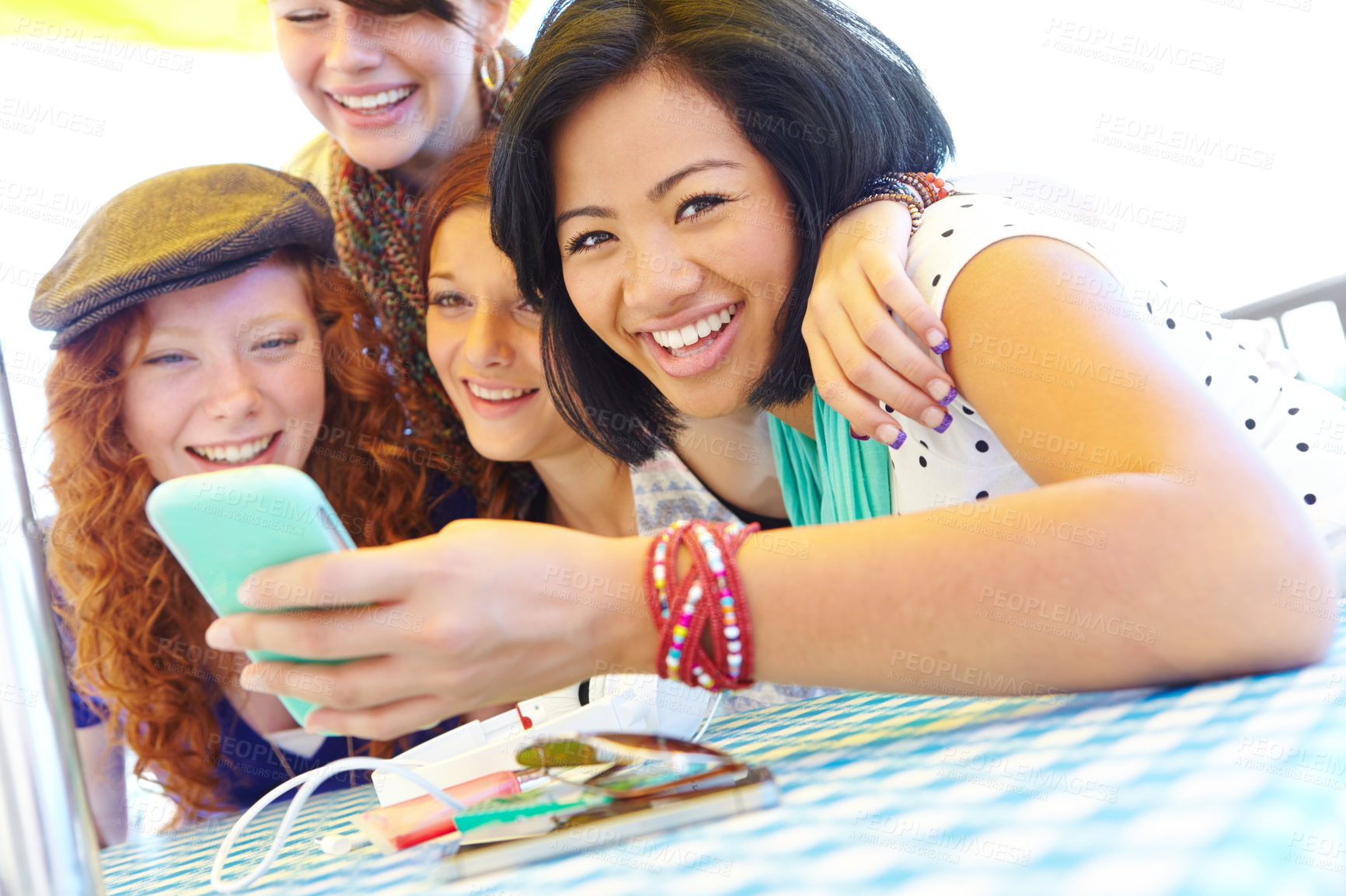 Buy stock photo A group of adolescent girls laughing as they look at something on a smartphone screen