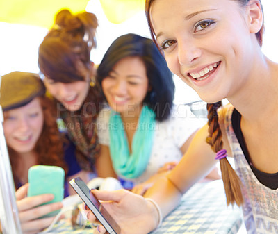 Buy stock photo A beautiful young adolescent girl holding a cellphone with her friends in the background