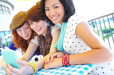 Buy stock photo A group of adolescent girls laughing as they look at something on a smartphone screen