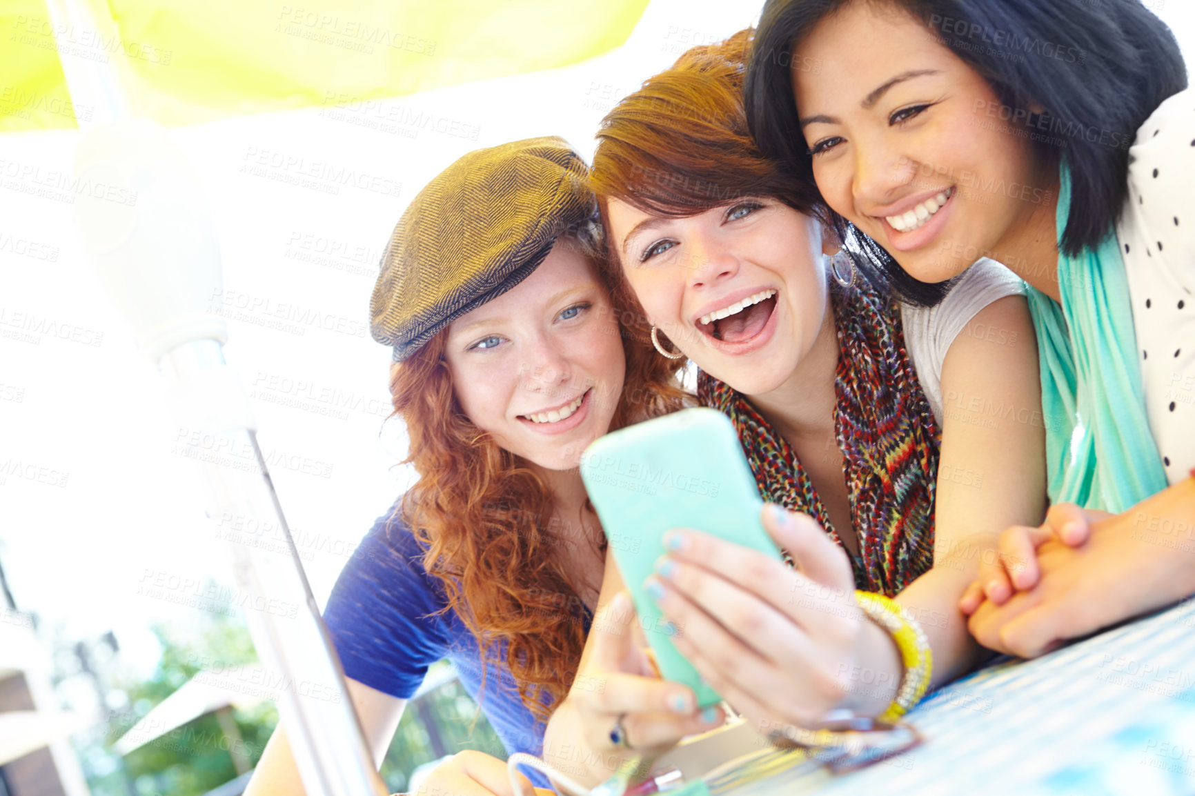 Buy stock photo A group of adolescent girls laughing as they look at something on a smartphone screen