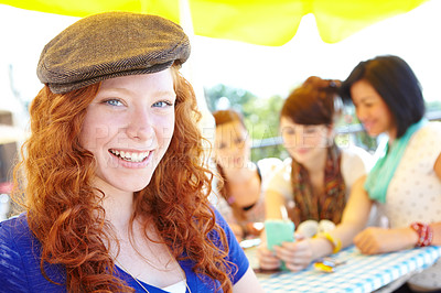 Buy stock photo A redheaded adolescent girl smiling at the camera with her friends sitting in the background