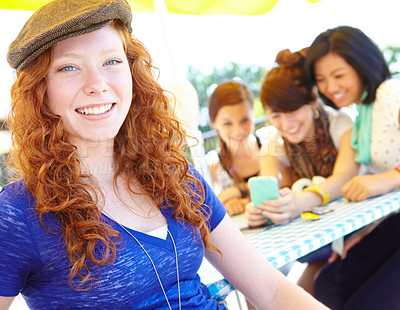 Buy stock photo A redheaded adolescent girl smiling at the camera with her friends sitting in the background