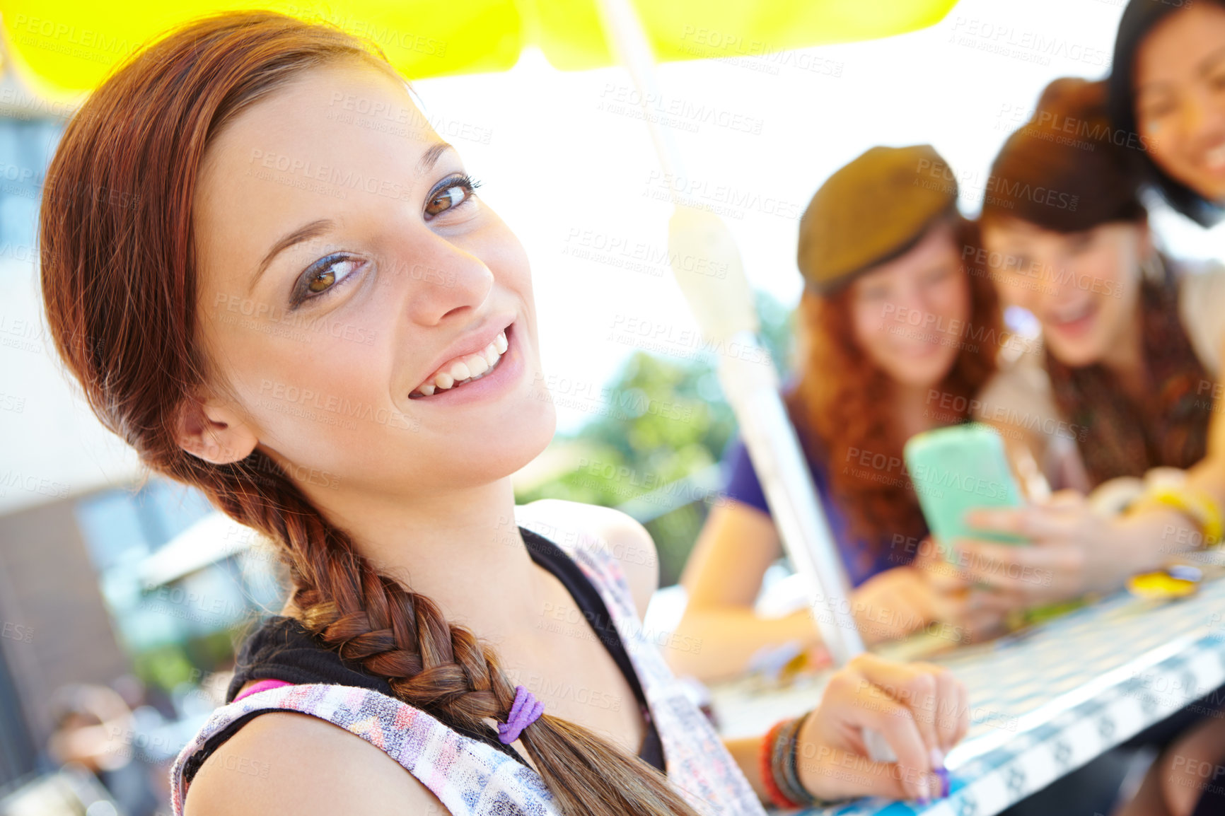 Buy stock photo An adolescent girl smiling at the camera with her friends sitting in the background