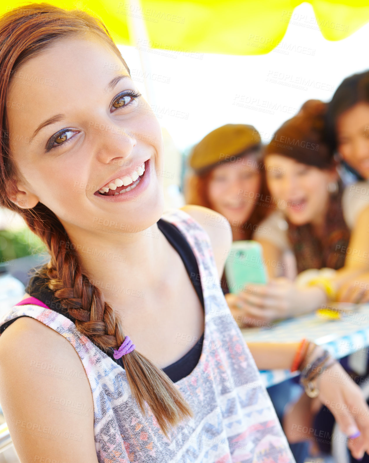 Buy stock photo An adolescent girl smiling at the camera with her friends sitting in the background