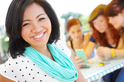 Buy stock photo An ethnic adolescent girl smiling at the camera with her friends sitting in the background