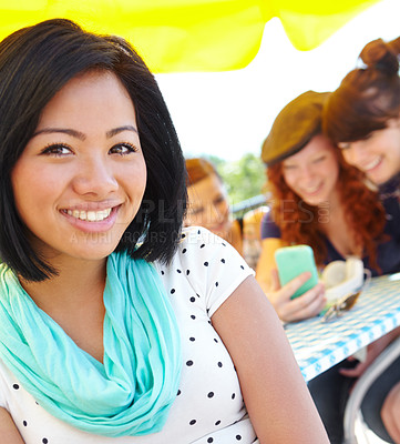 Buy stock photo An ethnic adolescent girl smiling at the camera with her friends sitting in the background