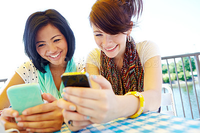 Buy stock photo Two teenage girls sitting outside texting on their cellphones