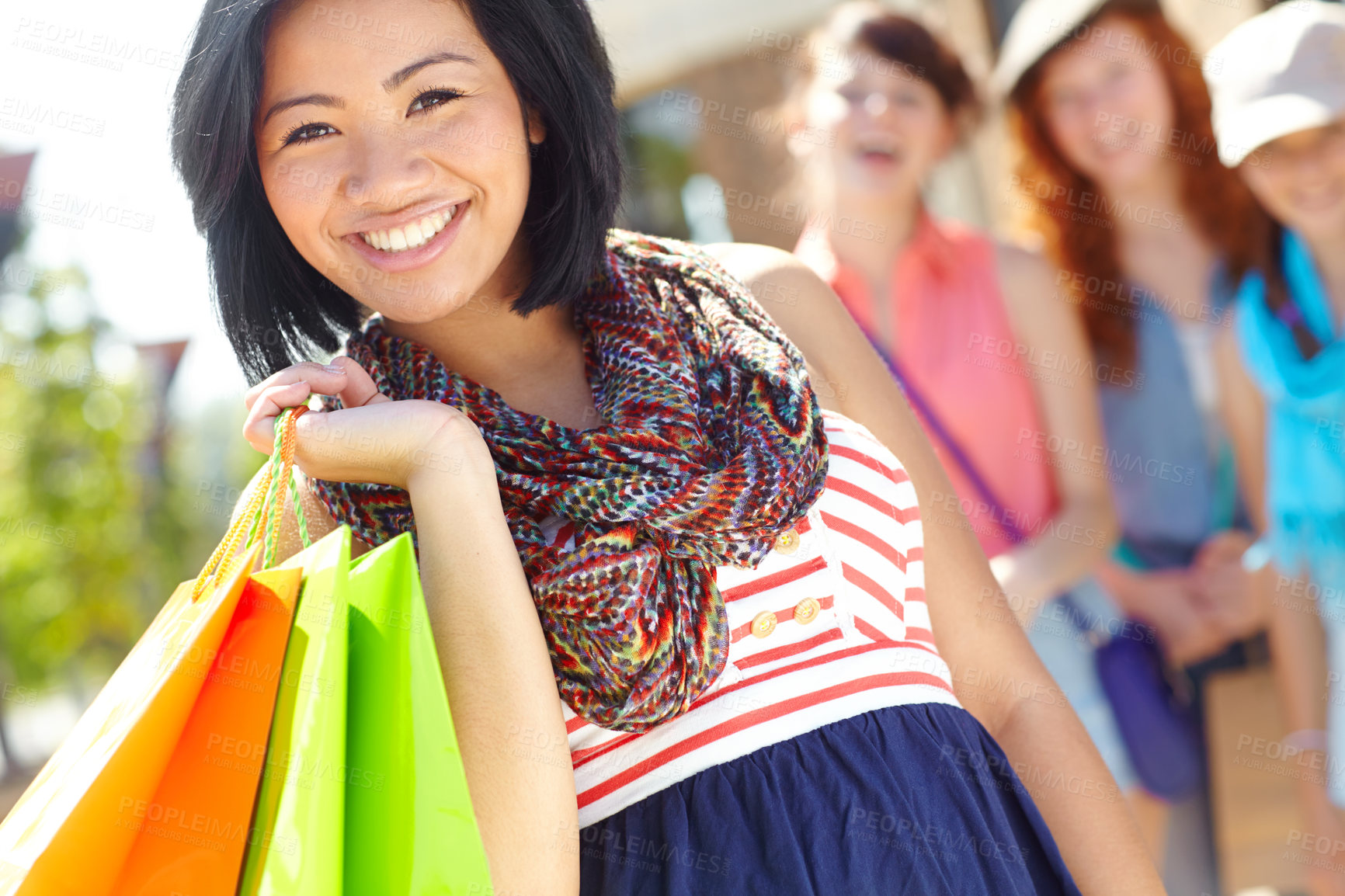 Buy stock photo A beautiful ethnic girl holding shopping bags and smiling with her friends in the background