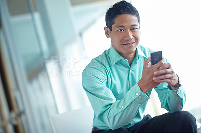 Buy stock photo A professional asian businessman sending a text message with his smartphone