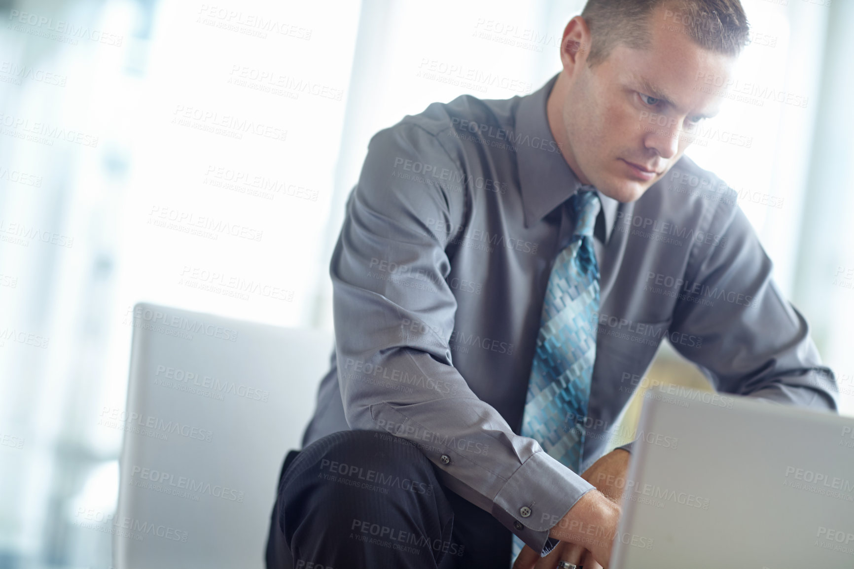 Buy stock photo A handsome young caucasian businessman working on his laptop