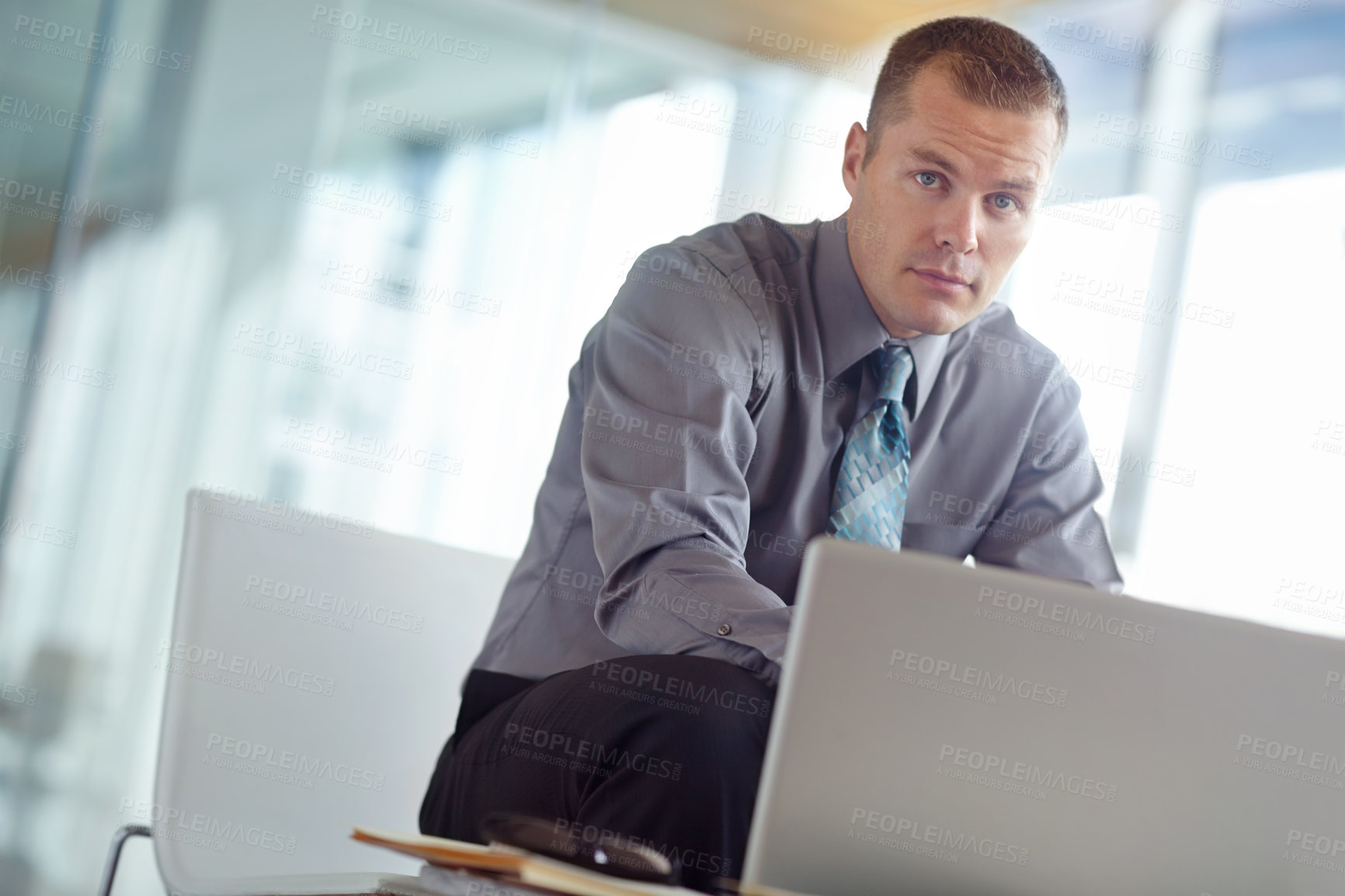 Buy stock photo A handsome young caucasian businessman working on his laptop