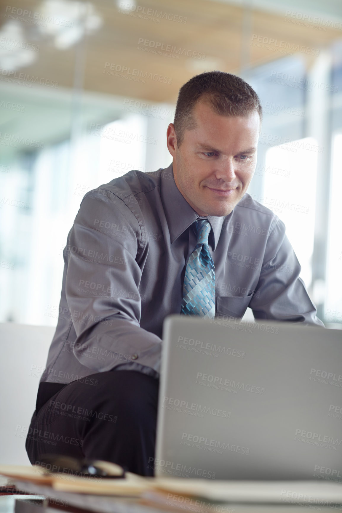 Buy stock photo A handsome young caucasian businessman working on his laptop