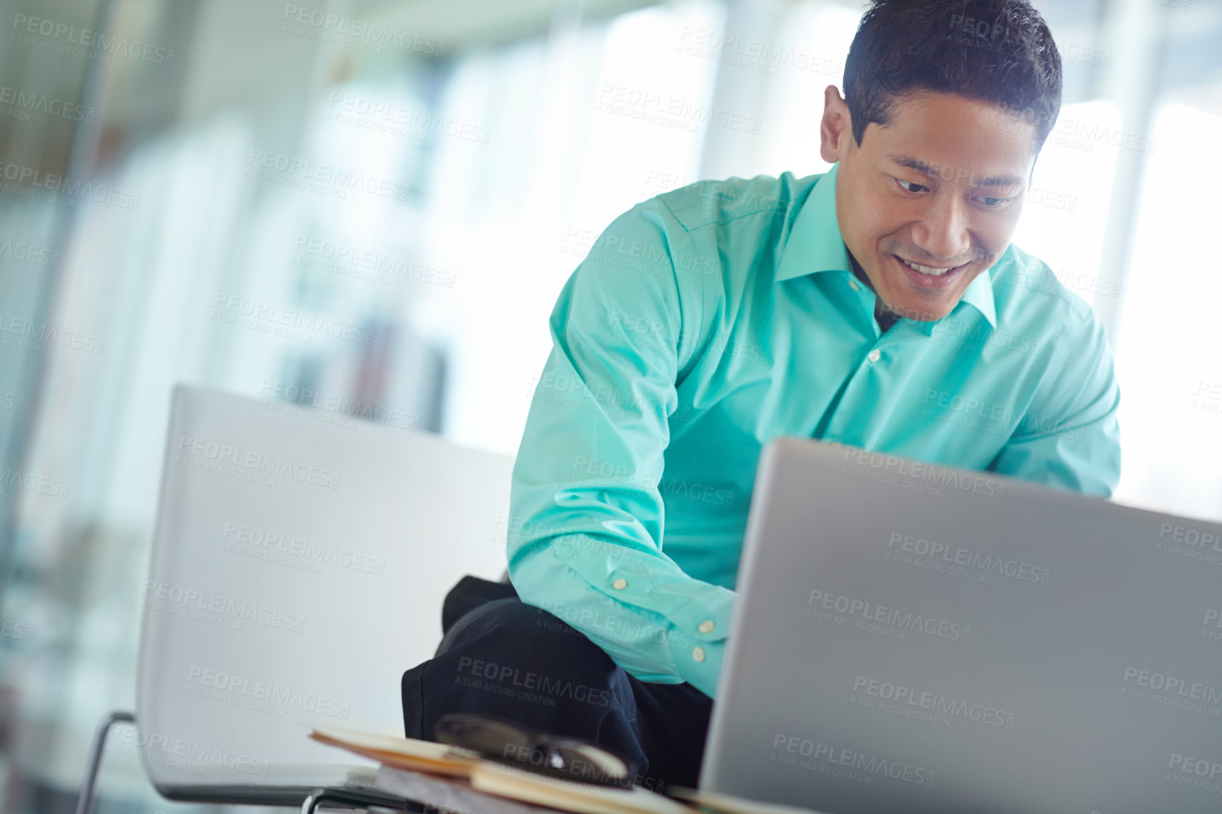 Buy stock photo Handsome young asian businessman using his laptop while at work