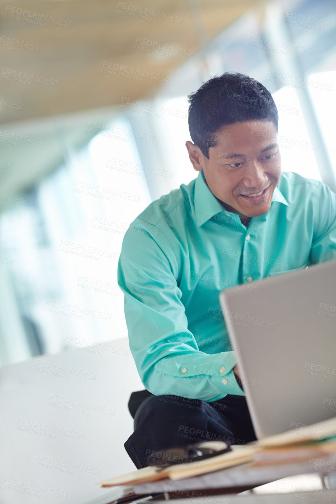 Buy stock photo Handsome young asian businessman using his laptop while at work